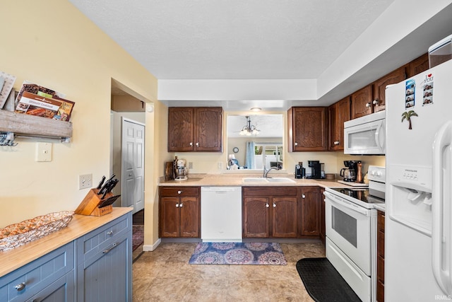 kitchen with light countertops, white appliances, a sink, and dark brown cabinets