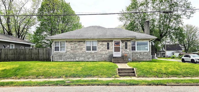 bungalow-style home featuring a front lawn, fence, stone siding, a chimney, and entry steps