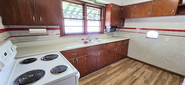 kitchen featuring electric range, tile walls, a sink, light countertops, and light wood-style floors