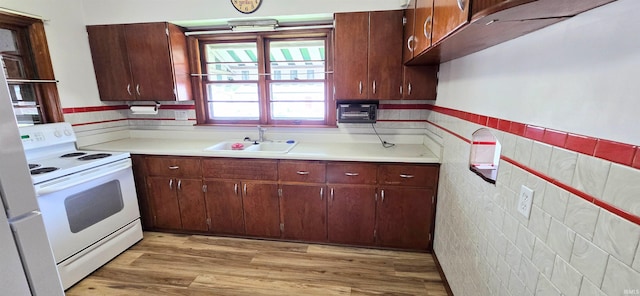 kitchen with light countertops, white range with electric stovetop, a sink, and light wood-type flooring