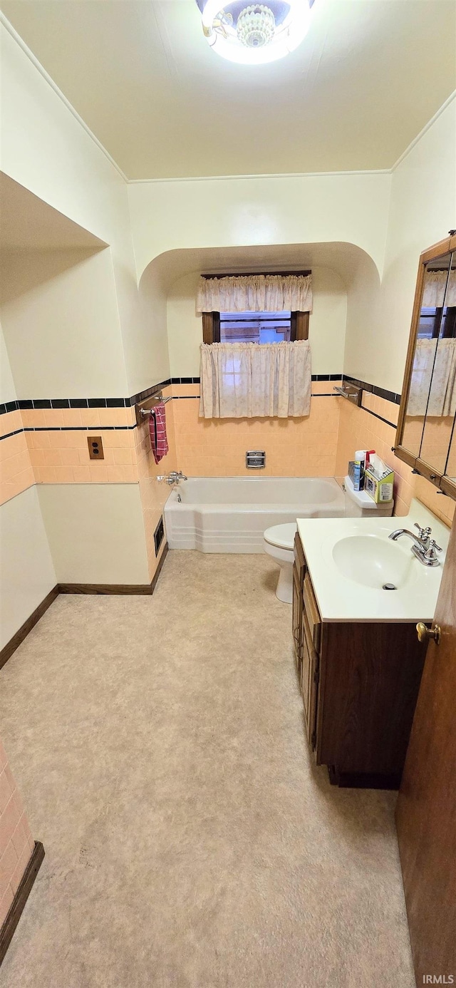 full bath featuring crown molding, a bathing tub, a wainscoted wall, vanity, and toilet