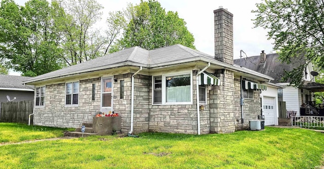 view of front facade with a front yard, fence, a chimney, and stone siding