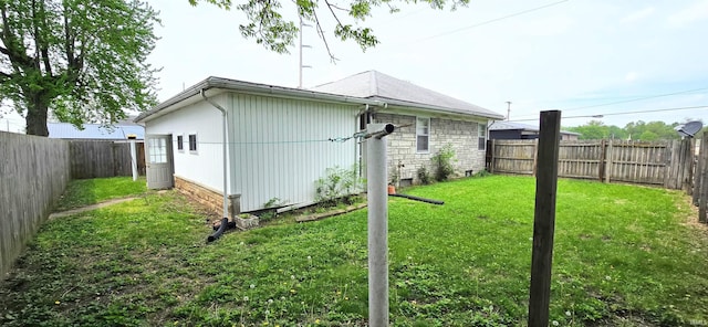 view of side of home featuring a fenced backyard, a yard, and stone siding