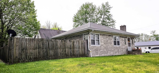 view of side of home featuring fence, a chimney, a yard, and stone siding