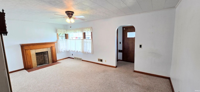 unfurnished living room with visible vents, a ceiling fan, carpet floors, a fireplace, and arched walkways