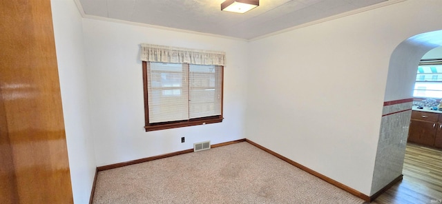 unfurnished room with arched walkways, baseboards, visible vents, and ornamental molding
