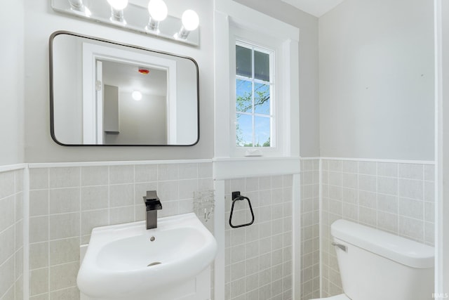 9231 Minnich Rd, Fort Wayne, IN 46816 - half bath featuring a sink, tile walls, a wainscoted wall, and toilet