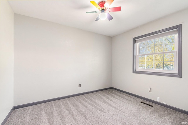 carpeted empty room with visible vents, baseboards, and ceiling fan