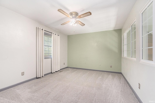carpeted empty room featuring a ceiling fan and baseboards