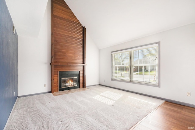unfurnished living room featuring high vaulted ceiling, baseboards, a fireplace, and light wood-type flooring