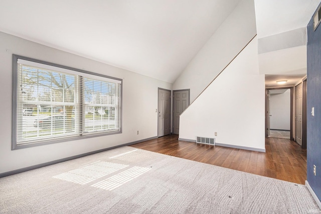 unfurnished living room with baseboards, visible vents, wood finished floors, and high vaulted ceiling