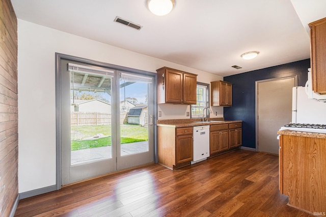 kitchen with white appliances, brown cabinetry, visible vents, and dark wood-style floors