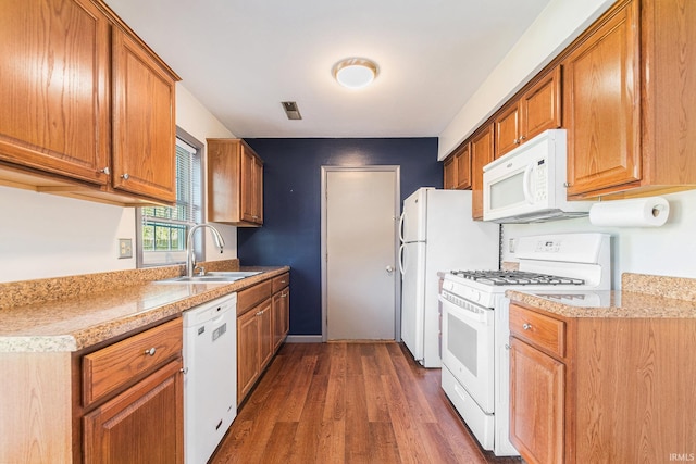 kitchen with a sink, brown cabinets, white appliances, and wood finished floors