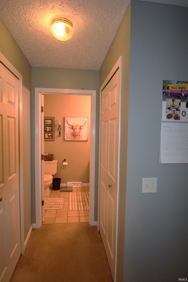 10035 N Turkey Creek Rd, Syracuse, IN 46567 - hallway featuring baseboards, tile patterned flooring, carpet, and a textured ceiling