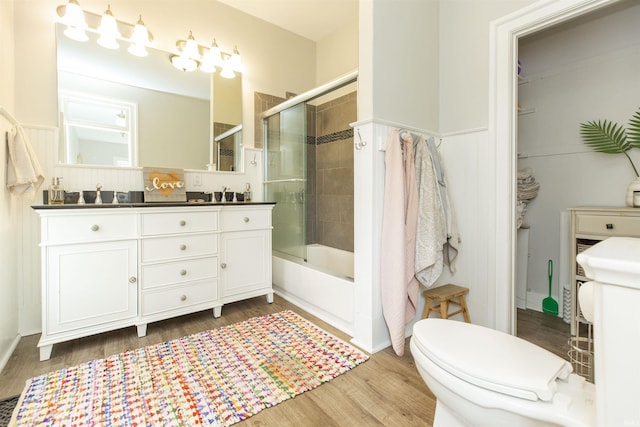 13546 Brick Rd, Granger, IN 46530 - full bathroom featuring double vanity, toilet, combined bath / shower with glass door, and wood finished floors