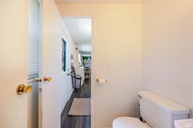 bathroom with baseboards, wood finished floors, and toilet