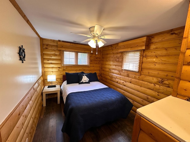 bedroom featuring ceiling fan, rustic walls, and dark wood-type flooring