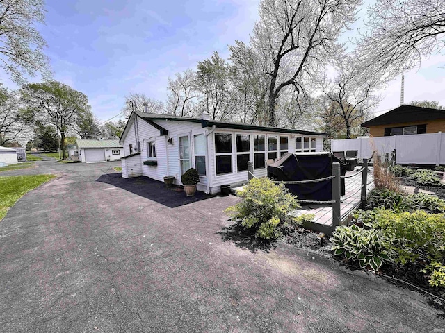 view of front facade with a detached garage, fence, and a chimney