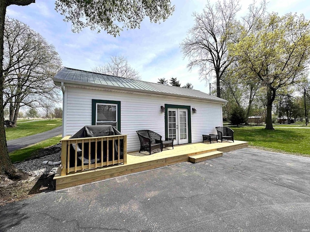 rear view of property with a yard, a deck, and metal roof