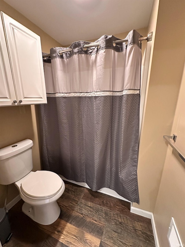 bathroom with toilet, baseboards, curtained shower, and wood finished floors