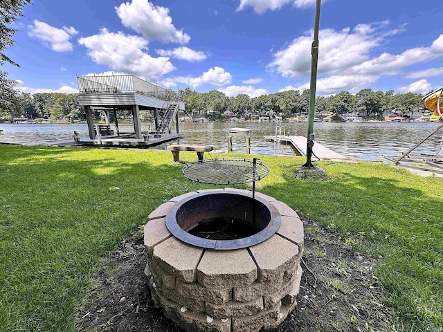 view of dock with a yard, a water view, and a fire pit