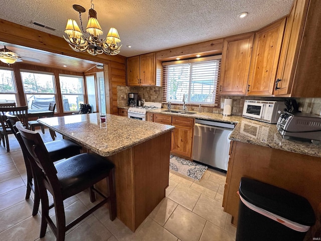 kitchen featuring backsplash, a textured ceiling, a sink, a notable chandelier, and white appliances