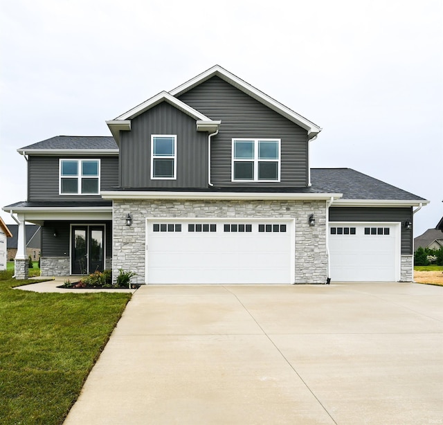 craftsman-style house featuring a garage, stone siding, driveway, and a front yard