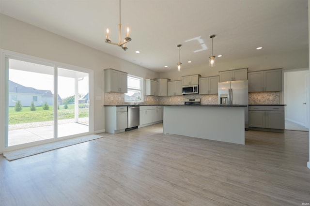 kitchen featuring stainless steel appliances, dark countertops, gray cabinetry, and an inviting chandelier