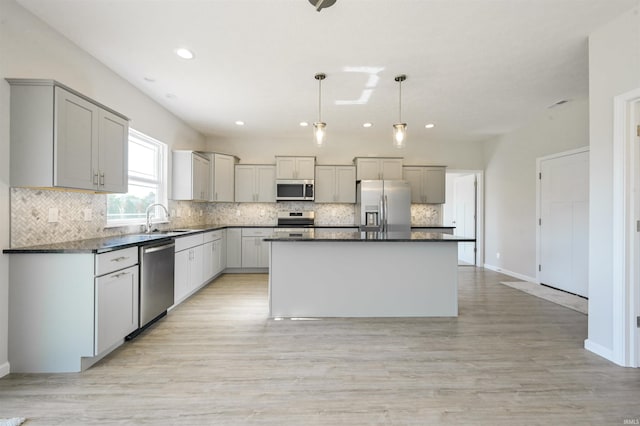 kitchen featuring stainless steel appliances, dark countertops, a sink, and tasteful backsplash
