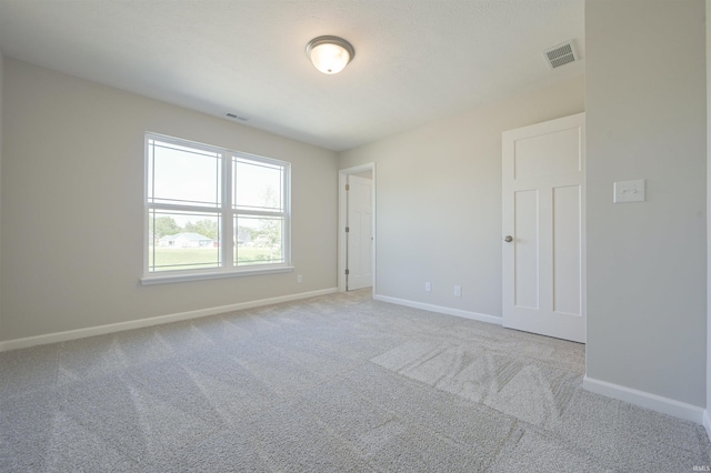 carpeted spare room featuring baseboards and visible vents