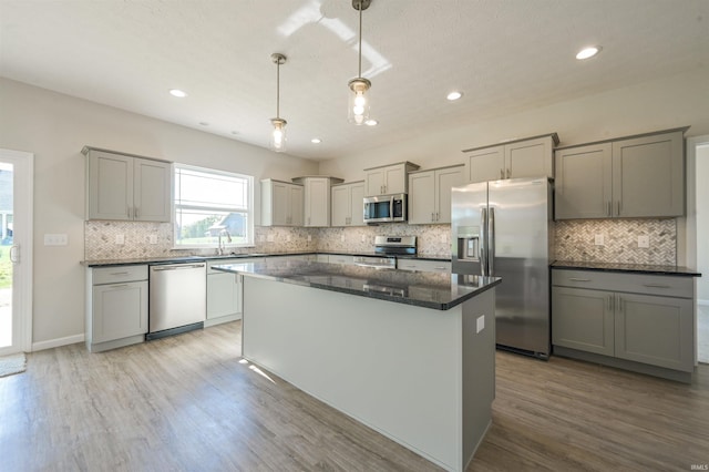 kitchen featuring decorative backsplash, a kitchen island, gray cabinets, light wood finished floors, and stainless steel appliances
