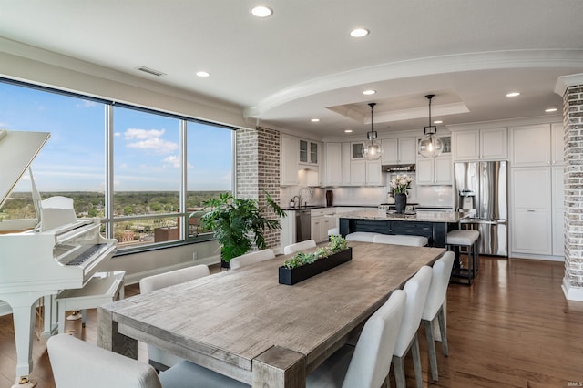 dining area with dark wood-style flooring, a tray ceiling, and recessed lighting