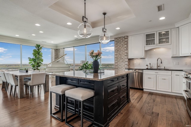 kitchen featuring decorative backsplash, dark wood-type flooring, white cabinets, a sink, and appliances with stainless steel finishes