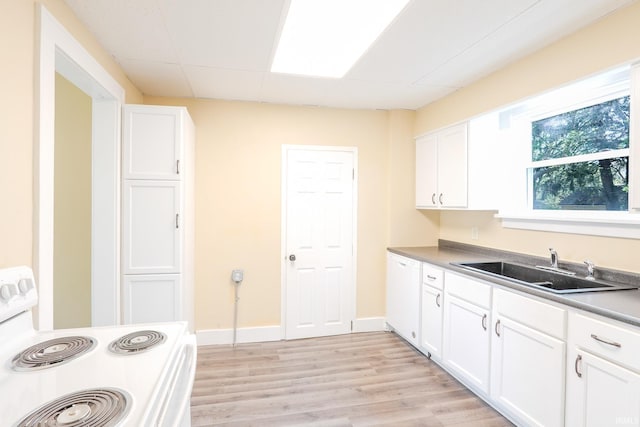 kitchen featuring white appliances, white cabinets, a sink, and light wood-style flooring