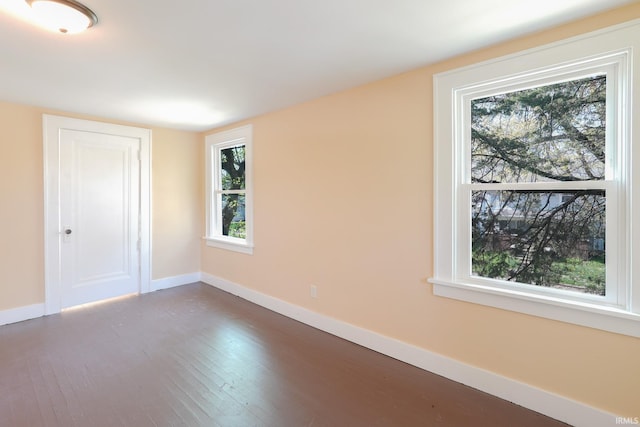 unfurnished room with baseboards, wood finished floors, and a wealth of natural light
