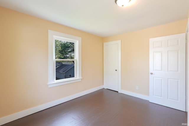 spare room with baseboards and dark wood-style flooring