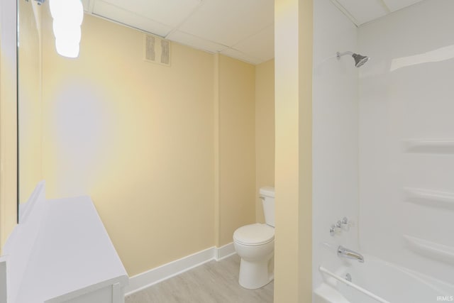 bathroom featuring visible vents, wood finished floors, toilet, shower / bathing tub combination, and a paneled ceiling