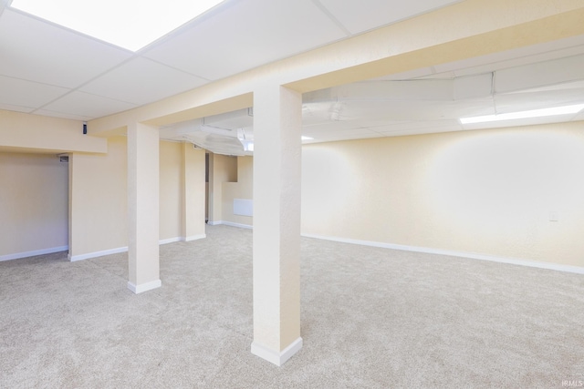 finished below grade area featuring baseboards, a paneled ceiling, and carpet