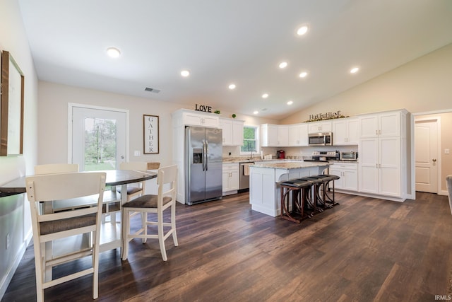 kitchen with visible vents, a kitchen island, dark wood-style floors, white cabinets, and stainless steel appliances