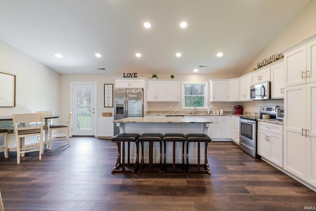 kitchen with a breakfast bar, a center island, white cabinetry, a sink, and stainless steel appliances
