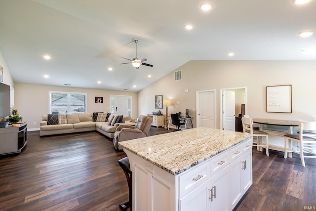 kitchen featuring a ceiling fan, visible vents, a center island, white cabinets, and dark wood-type flooring