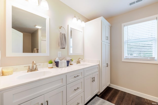 full bathroom featuring baseboards, visible vents, a sink, and wood finished floors