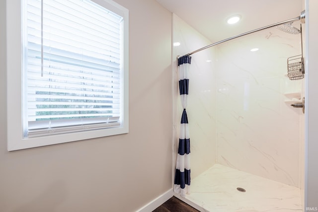 bathroom featuring baseboards, a marble finish shower, and wood finished floors