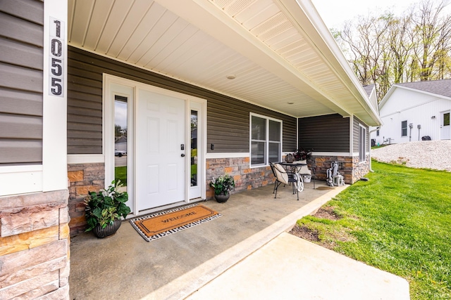 property entrance with a porch, a lawn, and stone siding