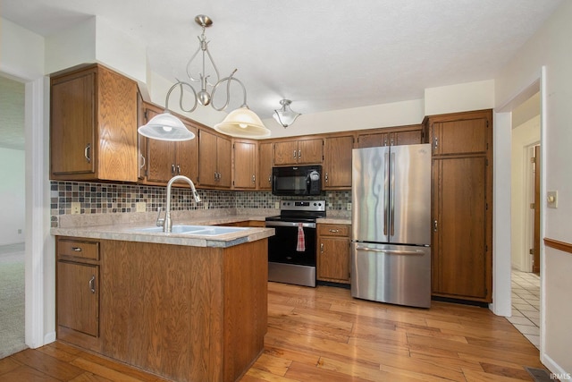 kitchen with brown cabinets, a peninsula, appliances with stainless steel finishes, and a sink