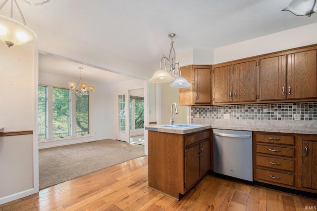 kitchen featuring brown cabinetry, dishwasher, a sink, light wood finished floors, and a peninsula