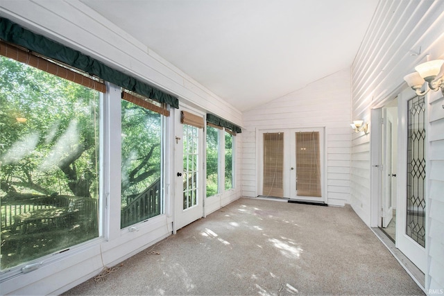 unfurnished sunroom with wood walls, carpet, french doors, and lofted ceiling