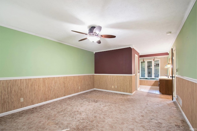 interior space featuring wooden walls, a ceiling fan, and a wainscoted wall