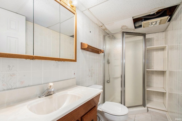 full bath with tile walls, a shower stall, vanity, tile patterned floors, and toilet