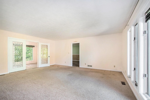 carpeted spare room featuring baseboards and visible vents
